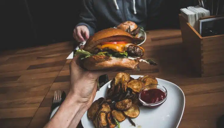 Un millenial mangeant un burger frites