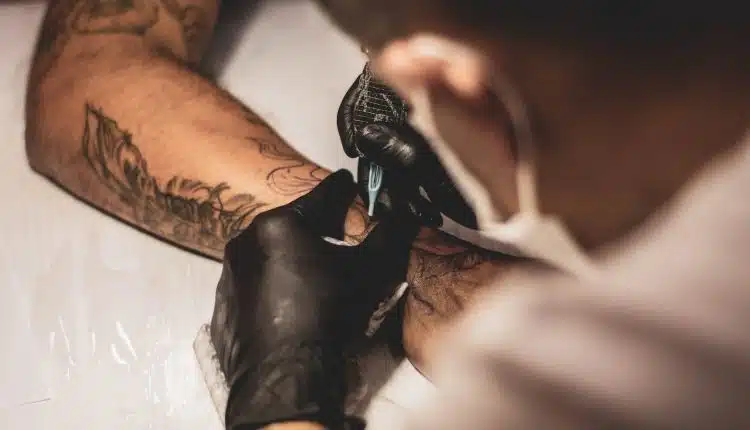 shallow focus photo of person tattooing person's right arm